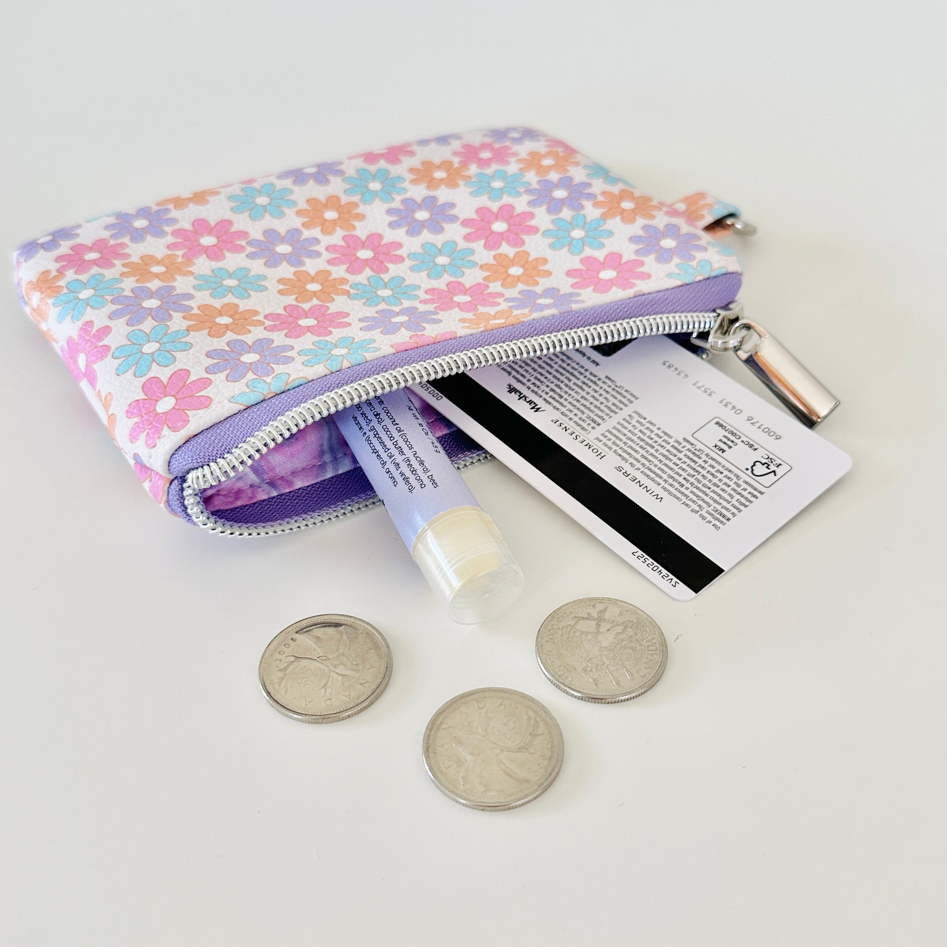 Floral patterned coin purse with cards and coins on a white background