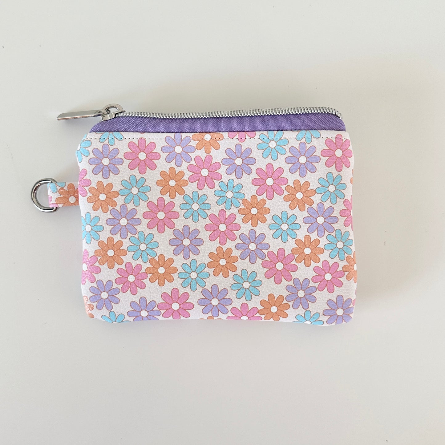 Floral patterned coin purse with cards and coins on a white background