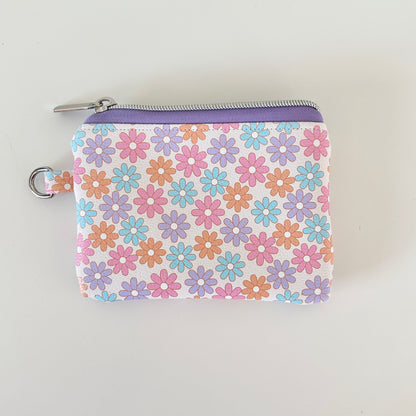 Floral patterned coin purse with cards and coins on a white background