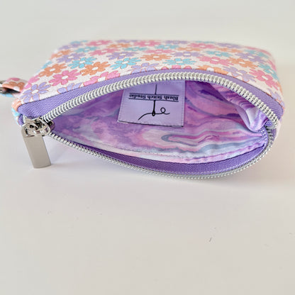 Floral patterned coin purse with cards and coins on a white background