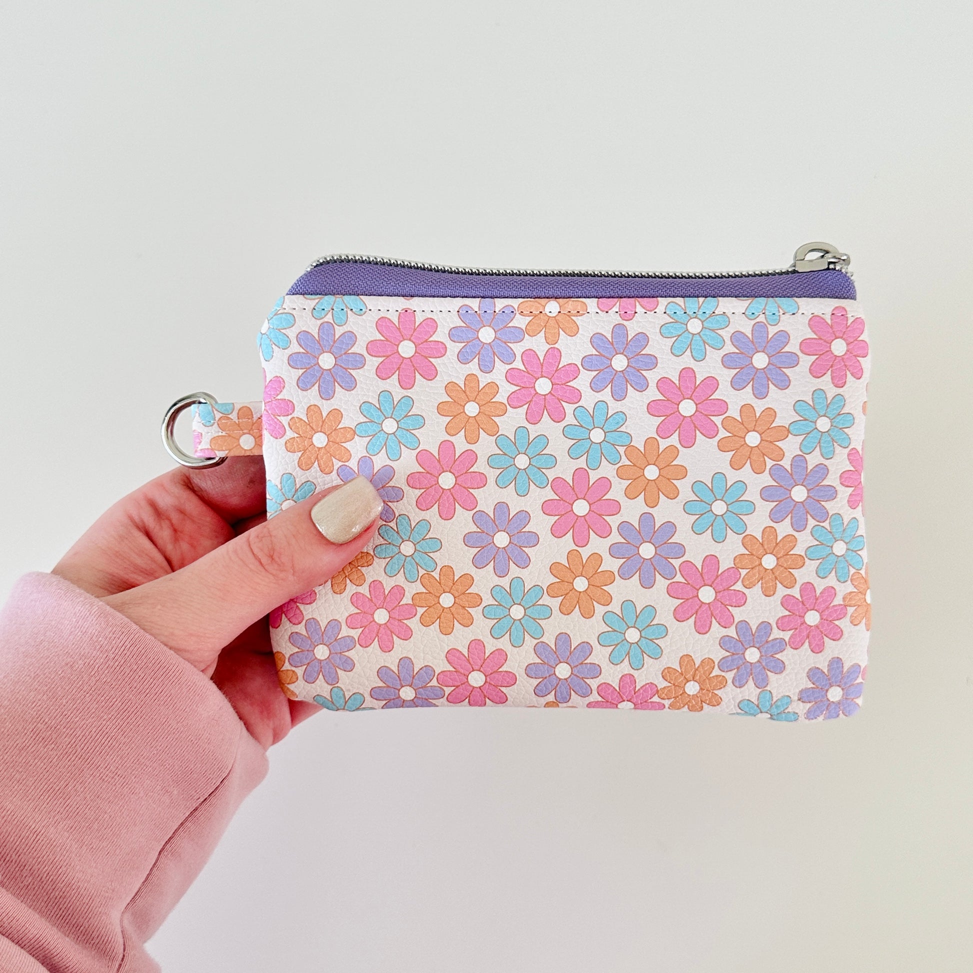 Floral patterned coin purse with cards and coins on a white background