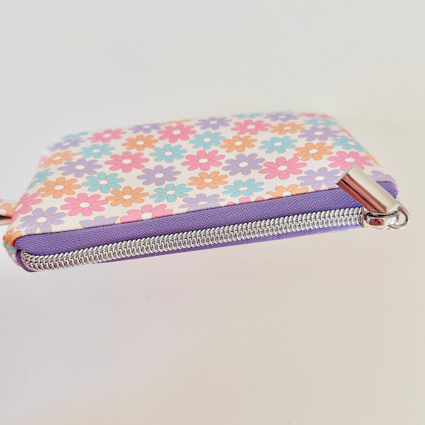 Floral patterned coin purse with cards and coins on a white background