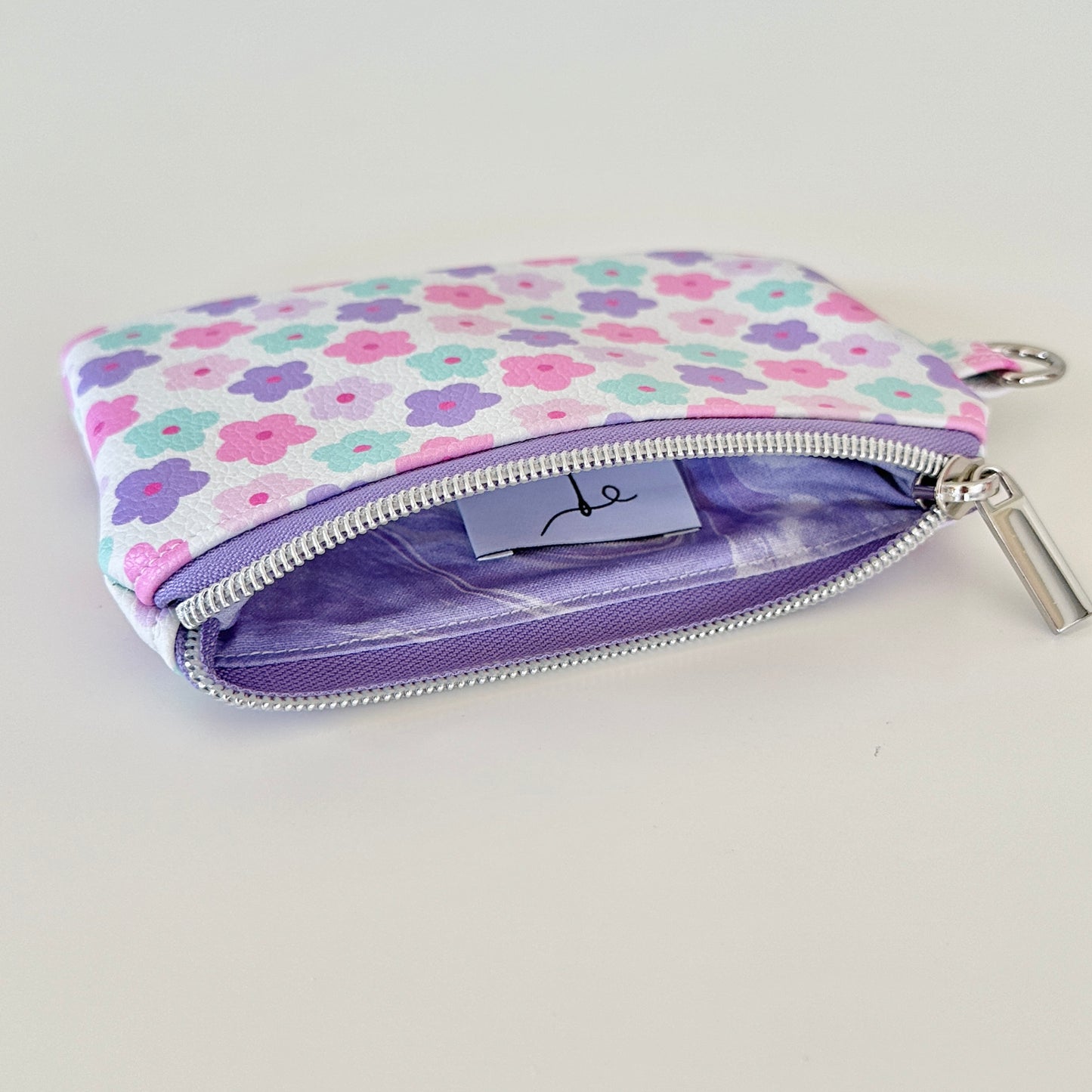 pink and purple Floral-patterned coin purse with coins and cards on a white background