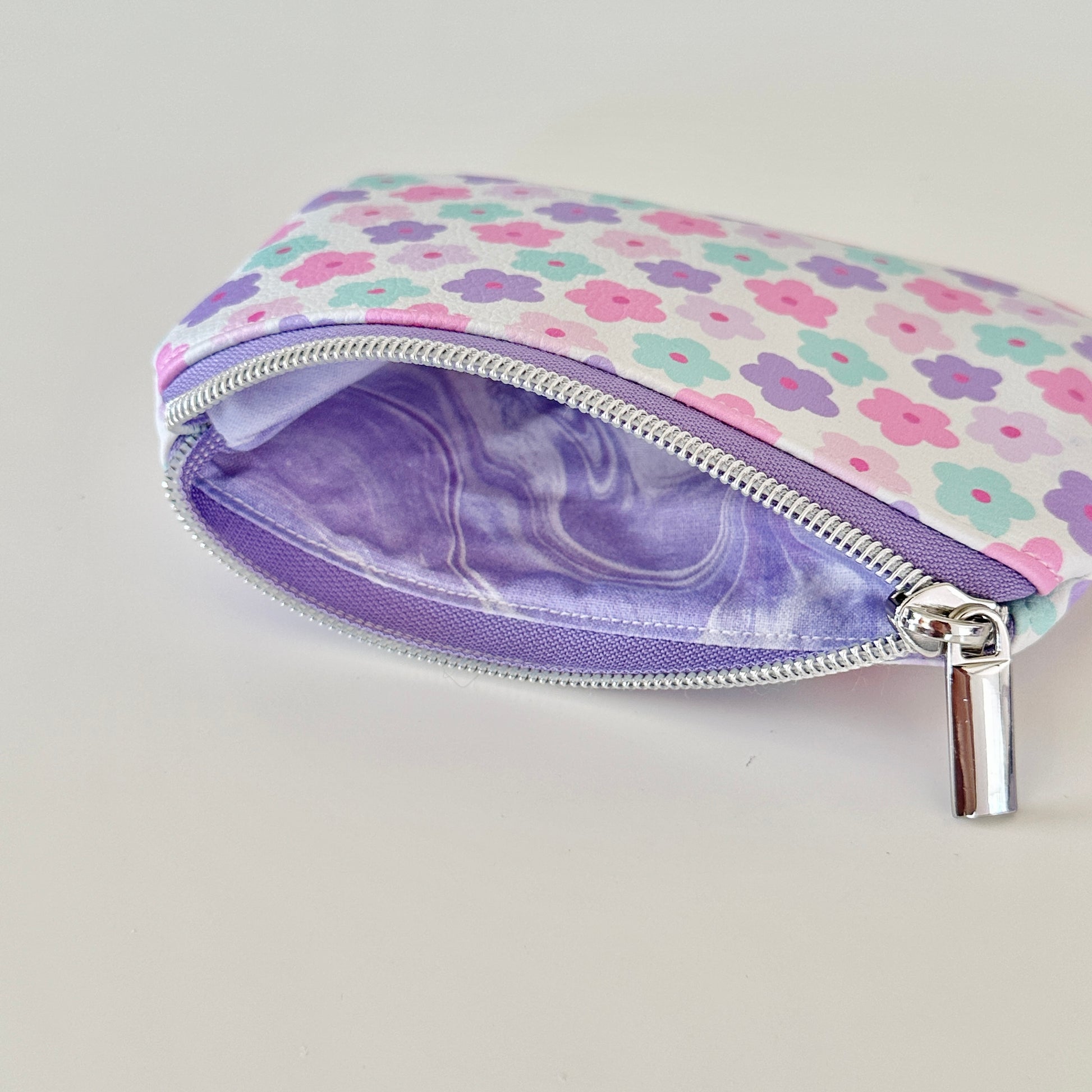 pink and purple Floral-patterned coin purse with coins and cards on a white background