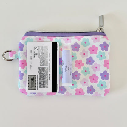pink and purple Floral-patterned coin purse with coins and cards on a white background
