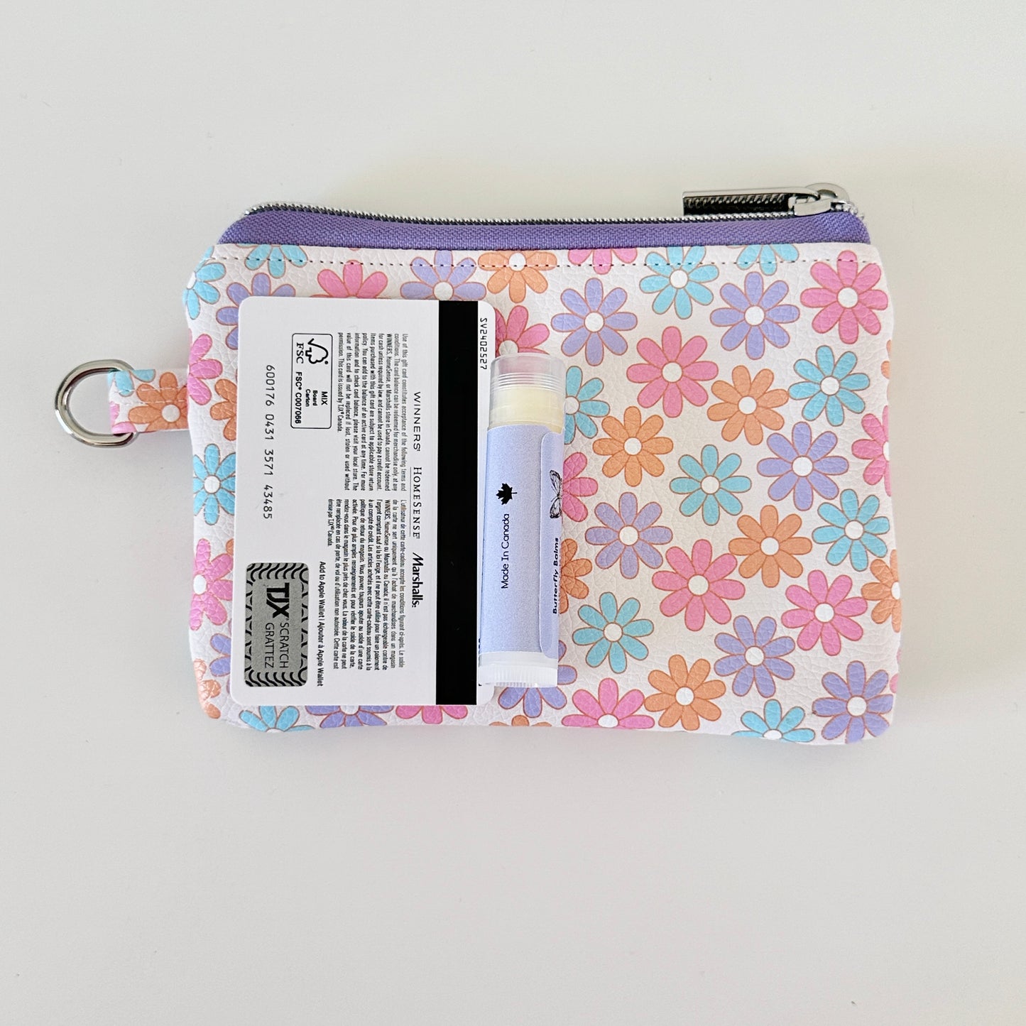 Floral patterned coin purse with cards and coins on a white background