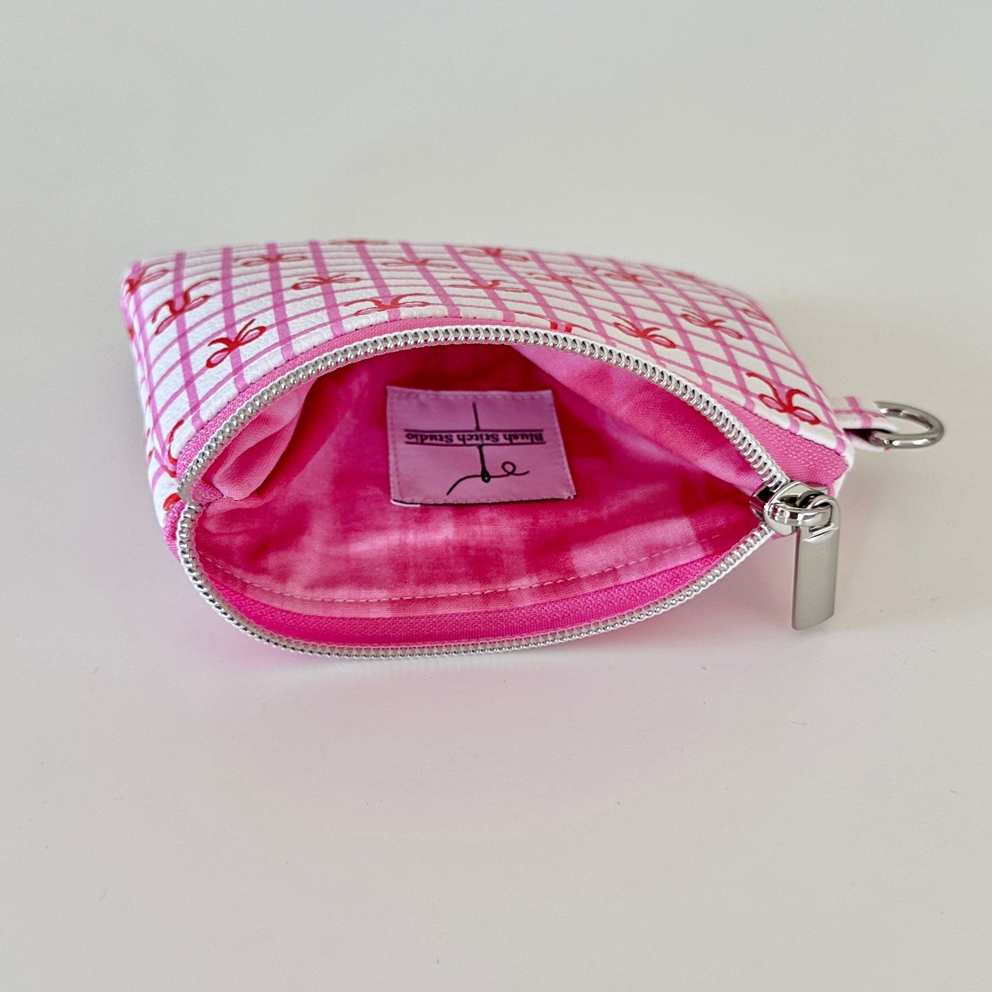 Pink checkered coquette vegan leather coin purse with red bows on a white background