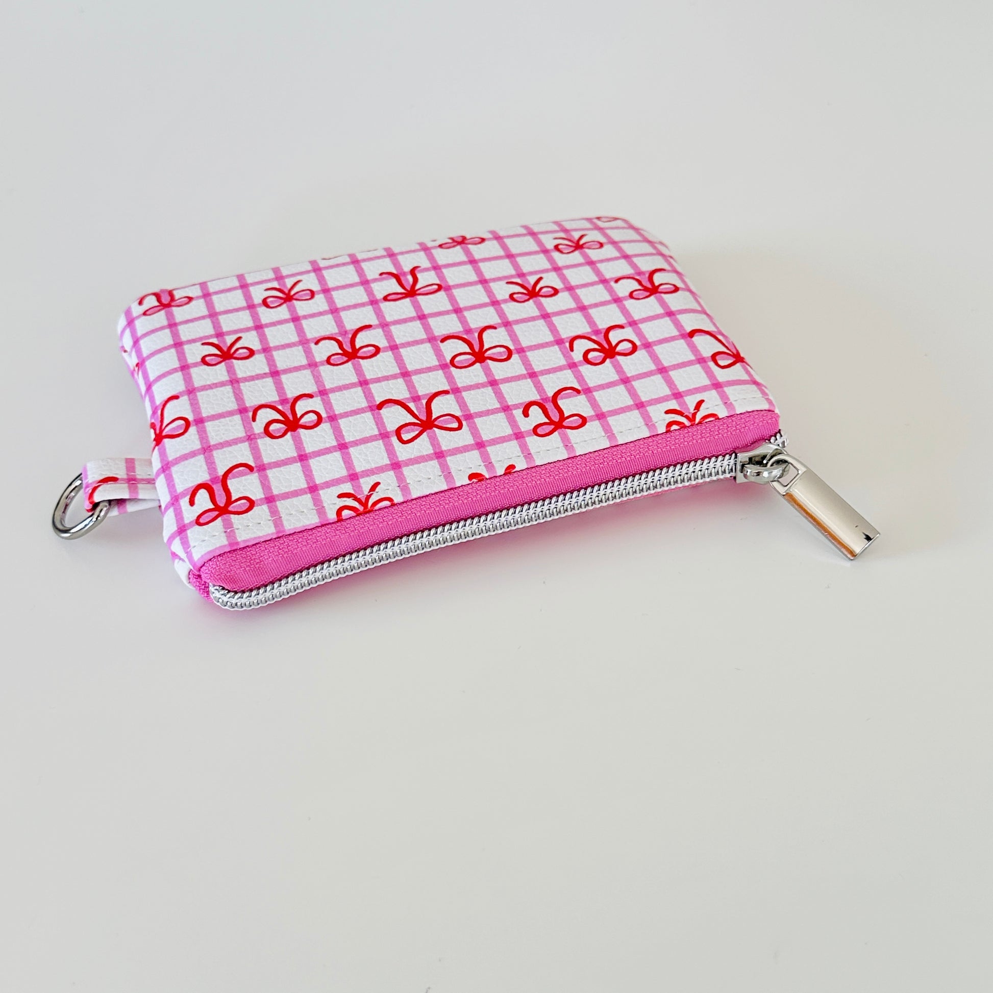 Pink checkered coquette vegan leather coin purse with red bows on a white background