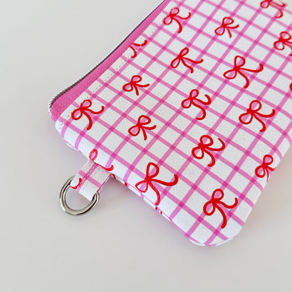 Pink checkered coquette vegan leather coin purse with red bows on a white background