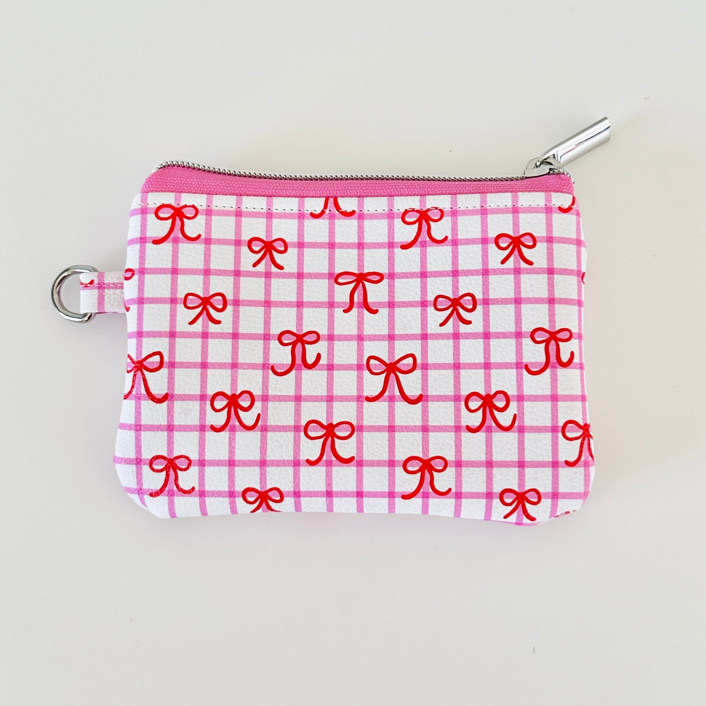 Pink checkered coquette vegan leather coin purse with red bows on a white background