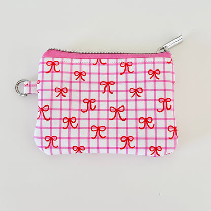 Pink checkered coquette vegan leather coin purse with red bows on a white background