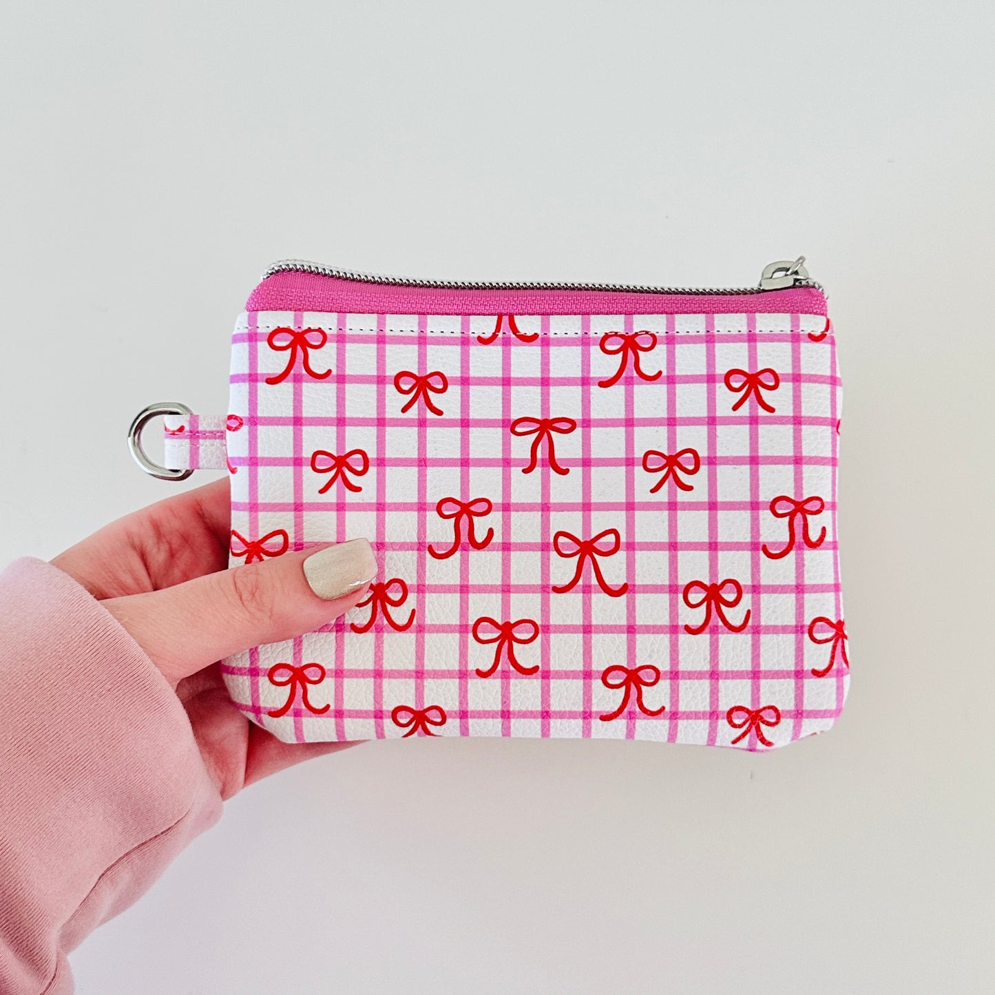 Pink checkered coquette vegan leather coin purse with red bows on a white background