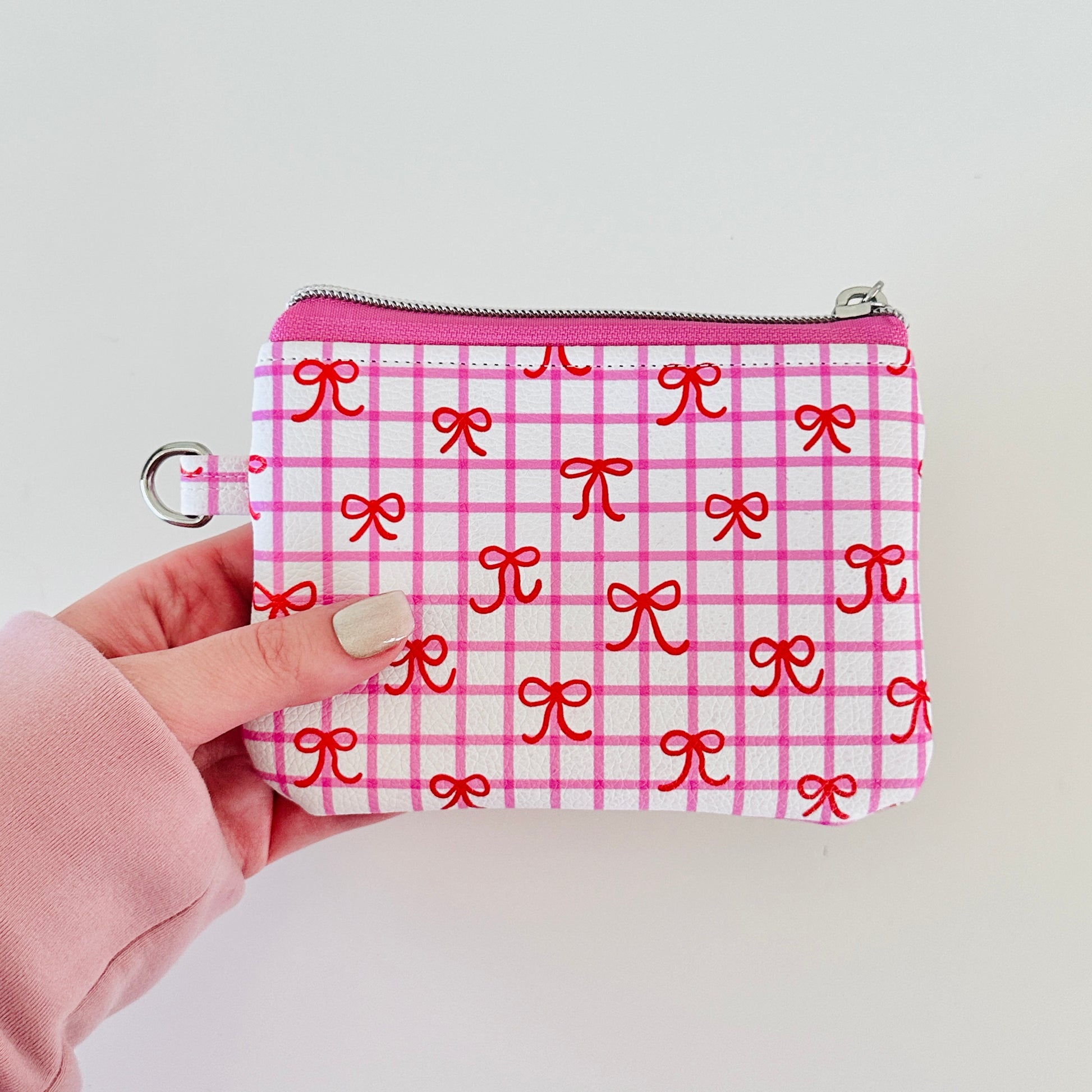 Pink checkered coquette vegan leather coin purse with red bows on a white background