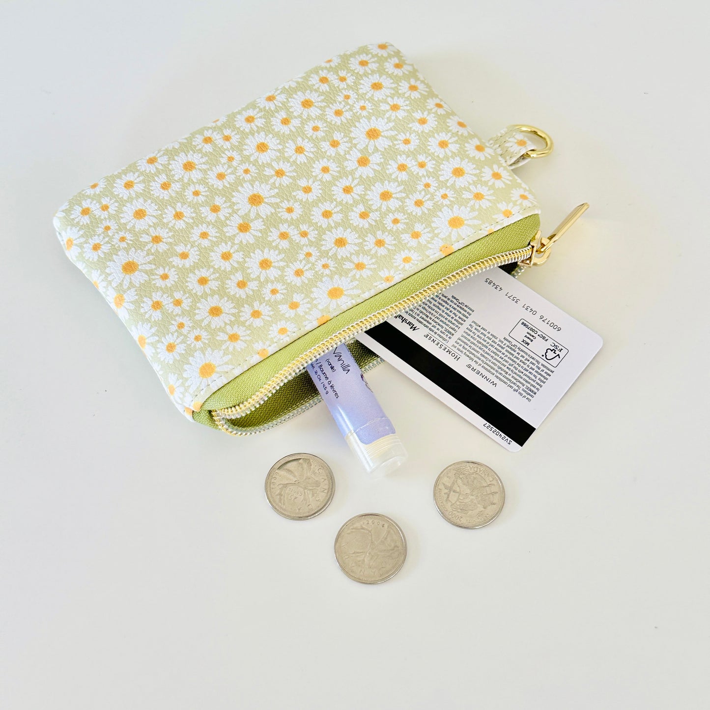 green daisy Floral-patterned coin purse  with coins and cards on a light background