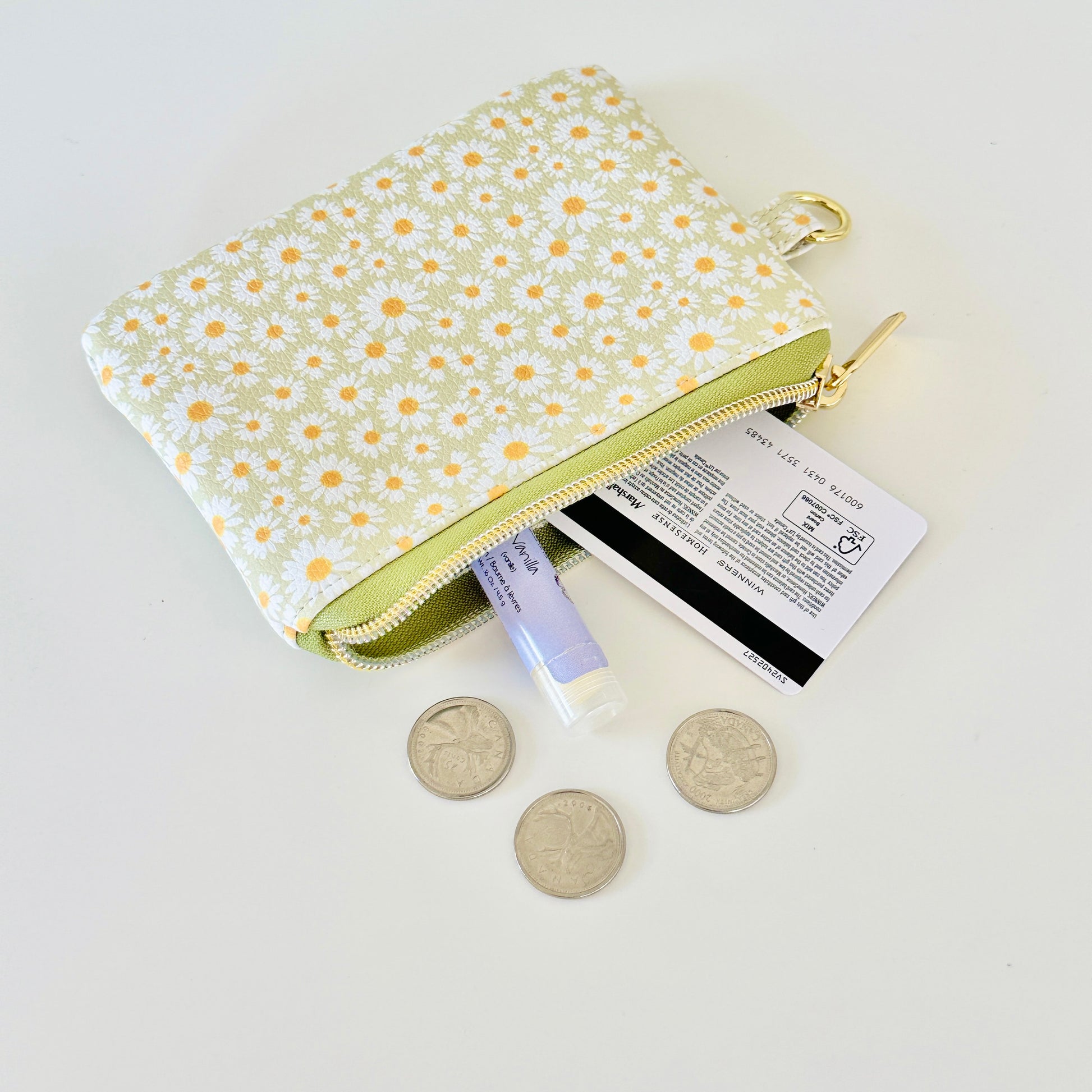 green daisy Floral-patterned coin purse  with coins and cards on a light background
