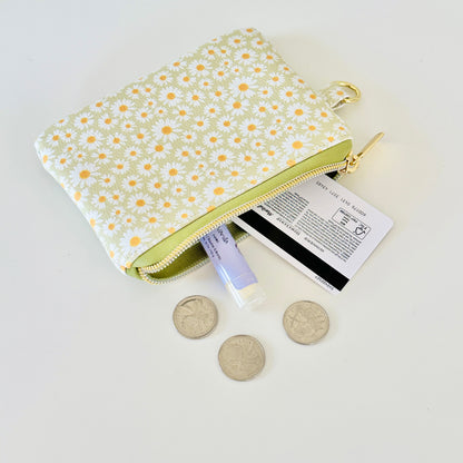 green daisy Floral-patterned coin purse  with coins and cards on a light background