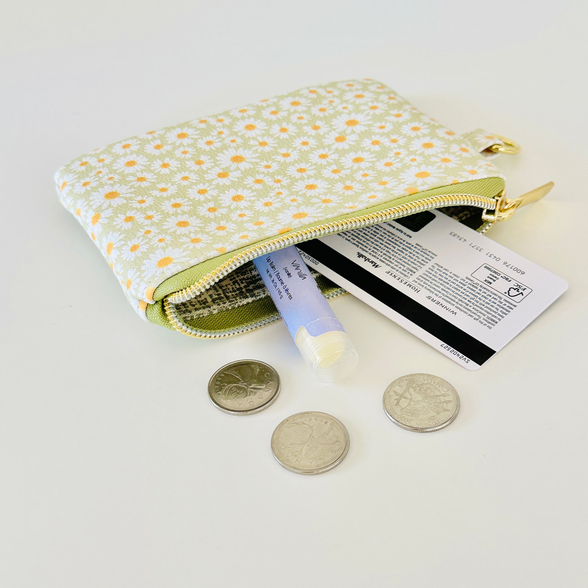 green daisy Floral-patterned coin purse  with coins and cards on a light background