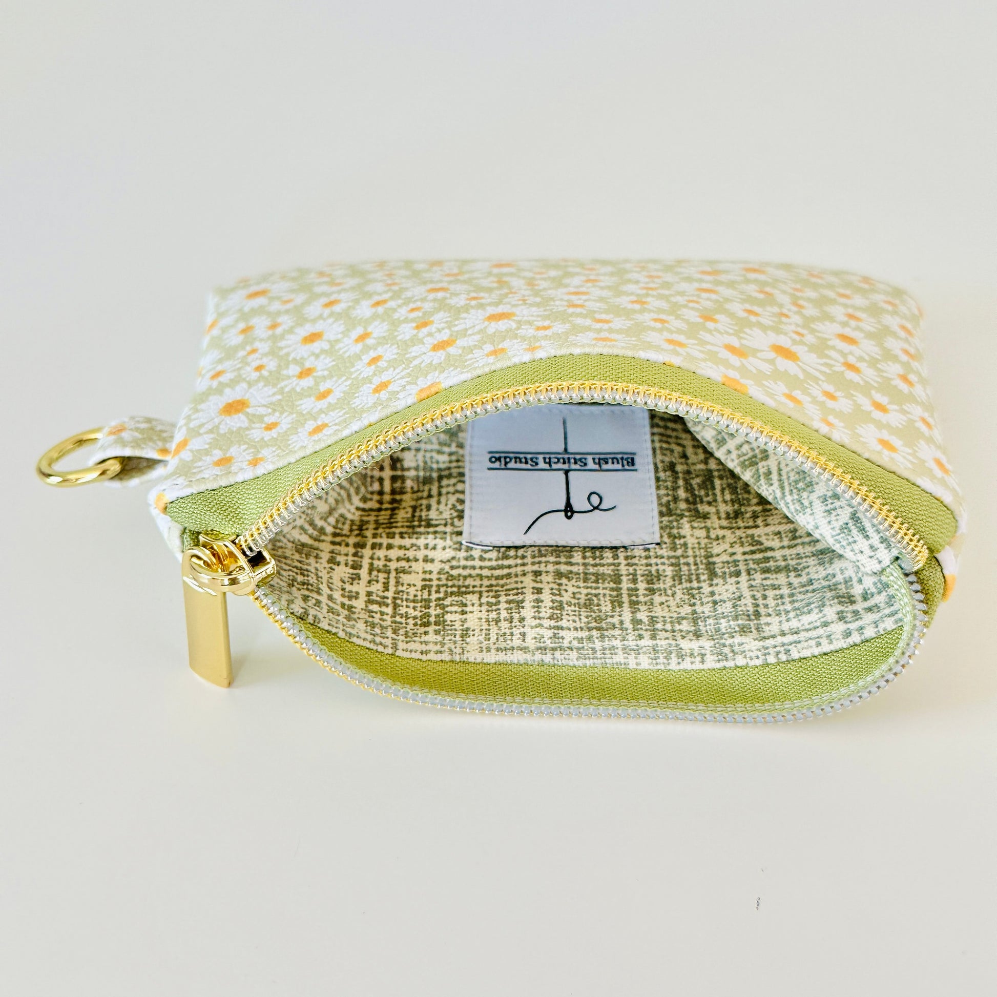 green daisy Floral-patterned coin purse  with coins and cards on a light background