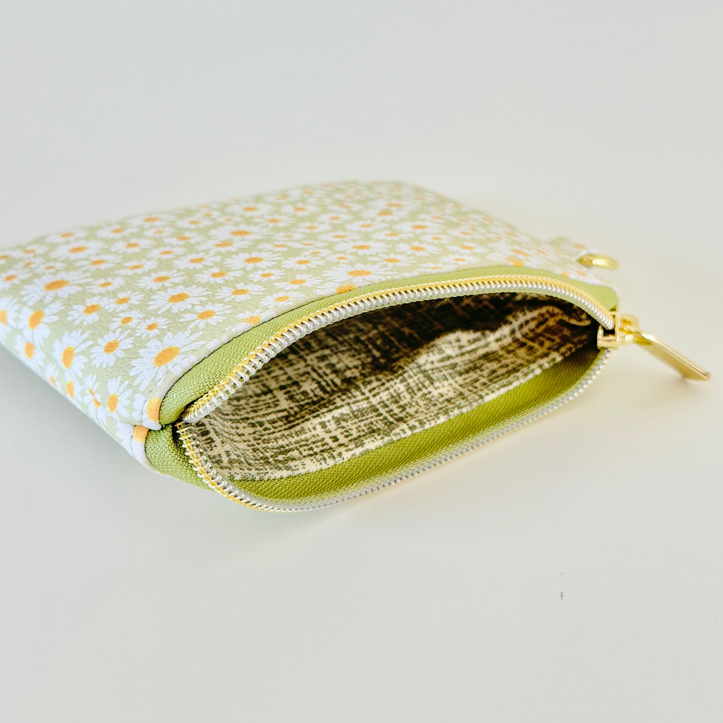 green daisy Floral-patterned coin purse  with coins and cards on a light background