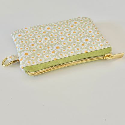 green daisy Floral-patterned coin purse  with coins and cards on a light background