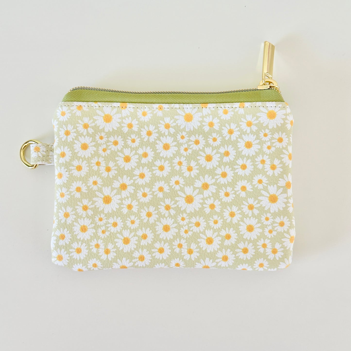 green daisy Floral-patterned coin purse  with coins and cards on a light background
