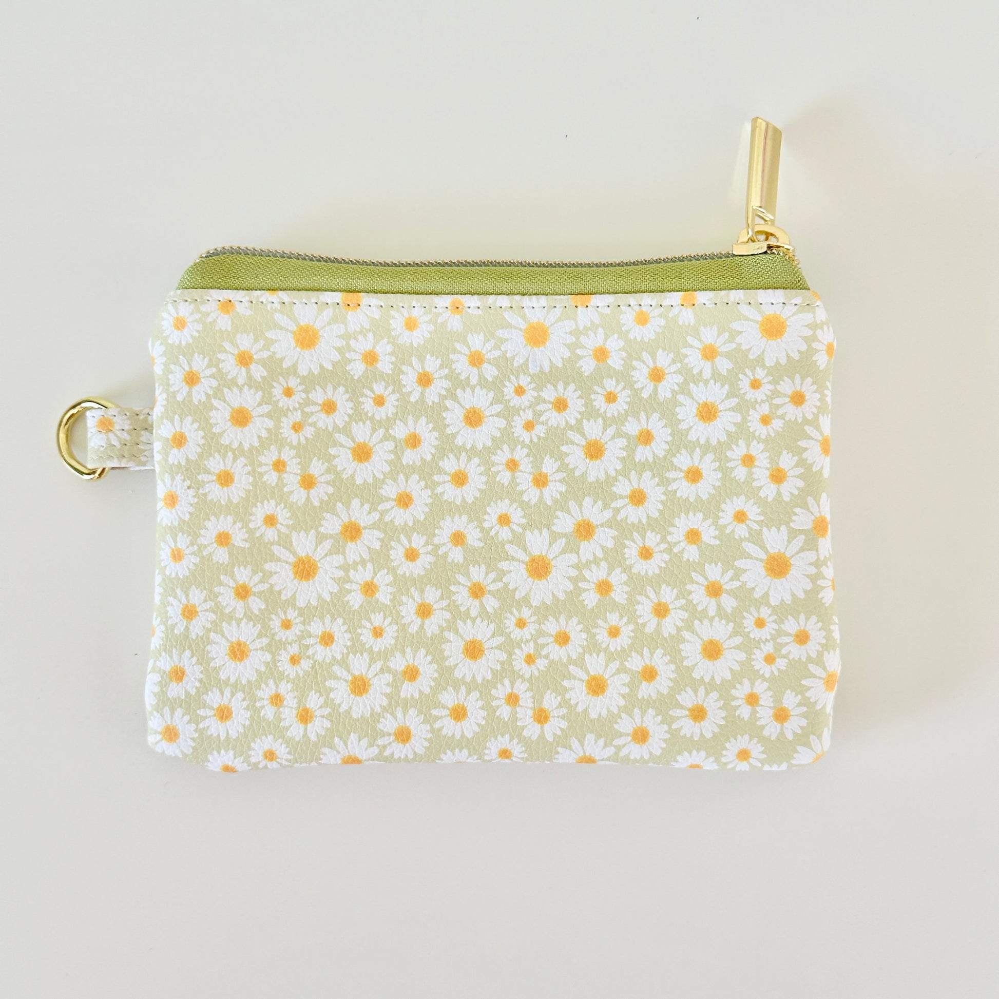 green daisy Floral-patterned coin purse  with coins and cards on a light background