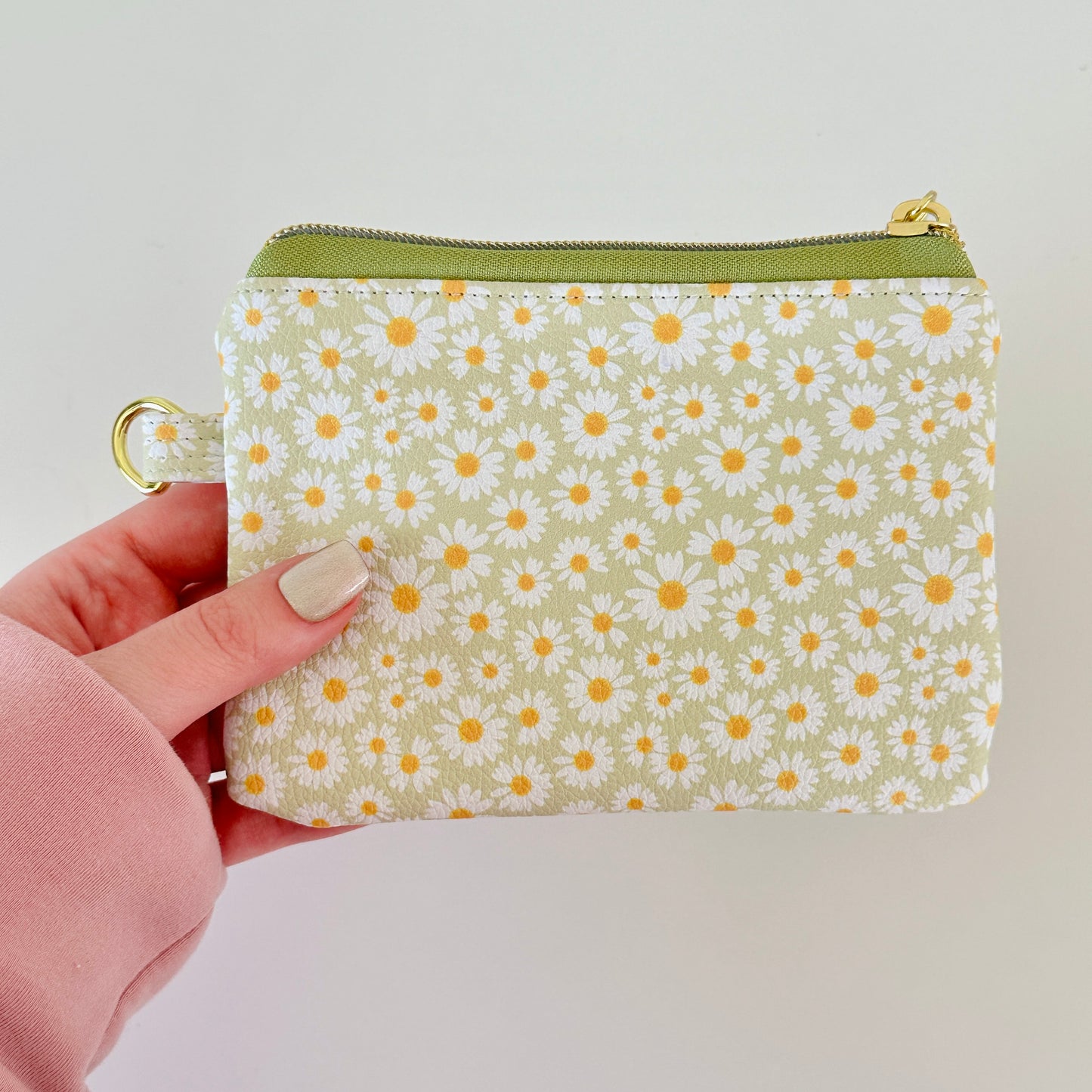 green daisy Floral-patterned coin purse  with coins and cards on a light background