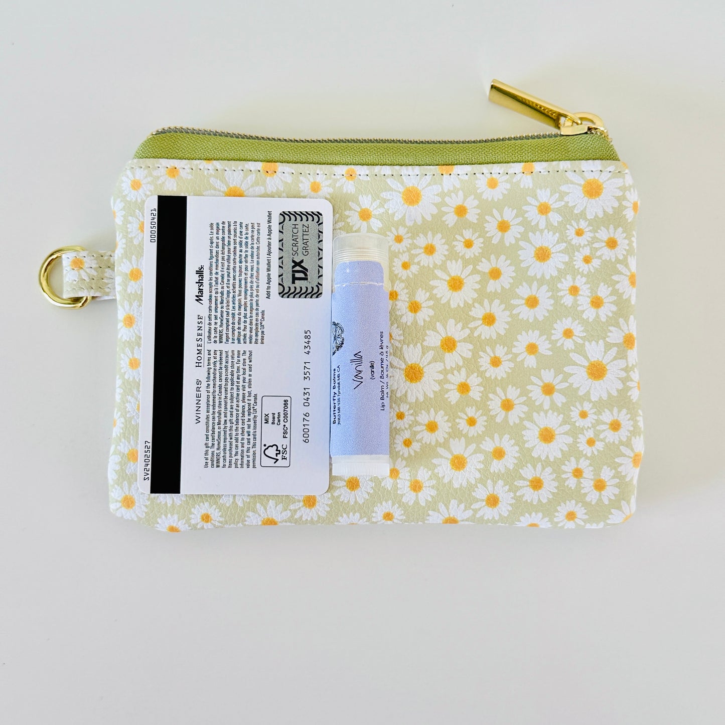 green daisy Floral-patterned coin purse  with coins and cards on a light background