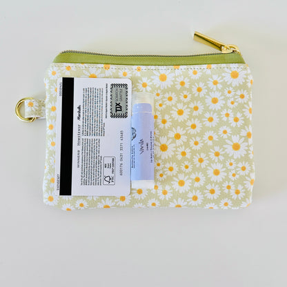 green daisy Floral-patterned coin purse  with coins and cards on a light background