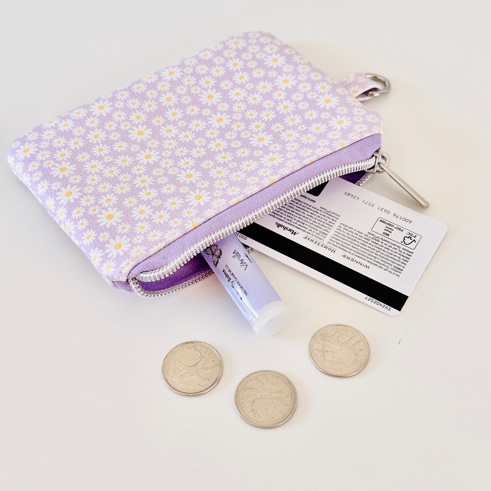 Purple floral-patterned coin purse with coins on a light gray background