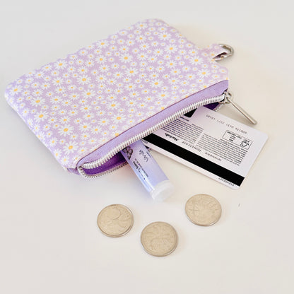 Purple floral-patterned coin purse with coins on a light gray background