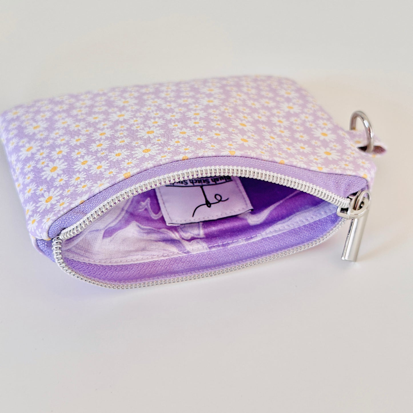 Purple floral-patterned coin purse with coins on a light gray background