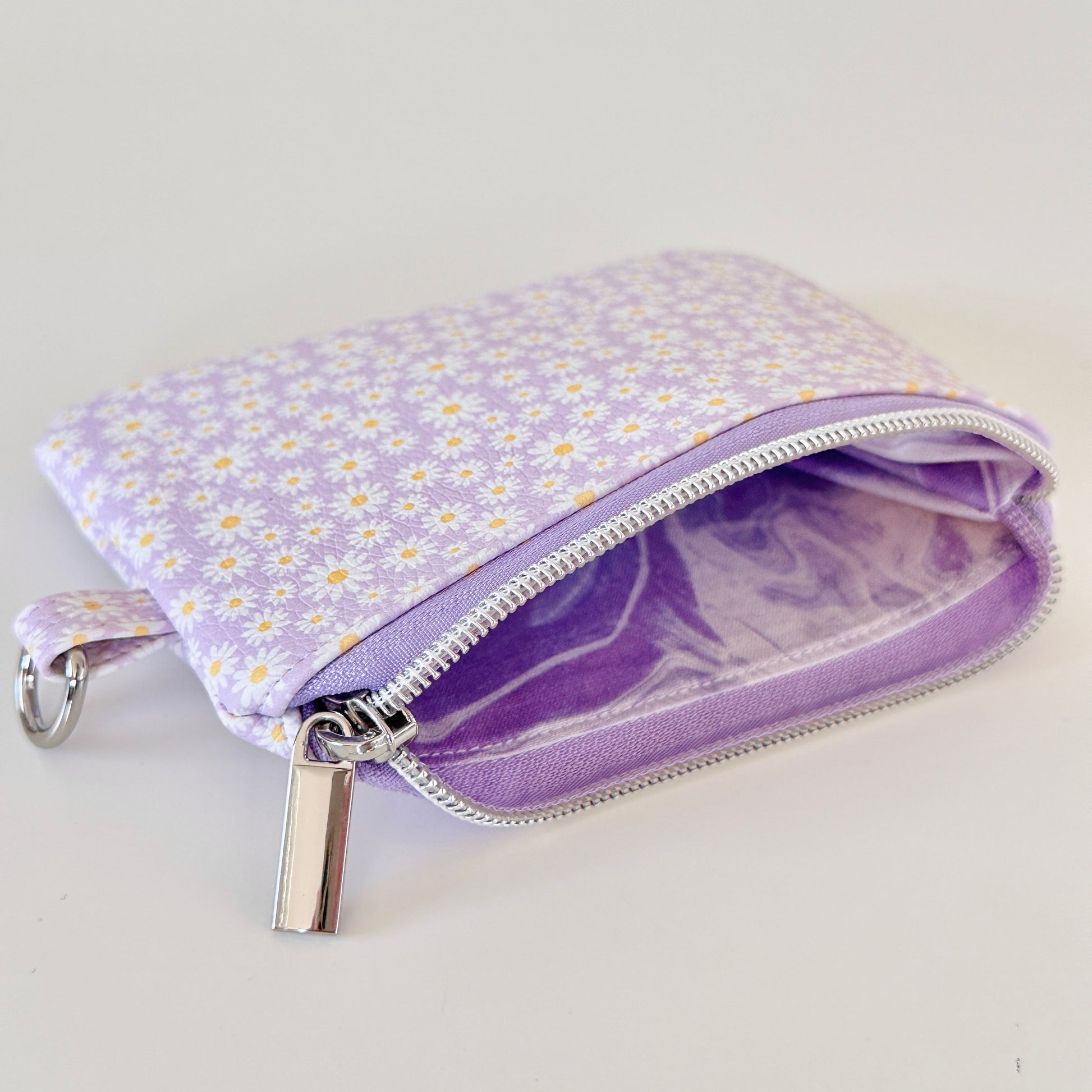 Purple floral-patterned coin purse with coins on a light gray background