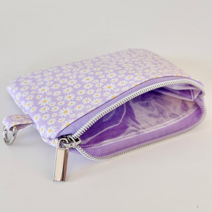 Purple floral-patterned coin purse with coins on a light gray background