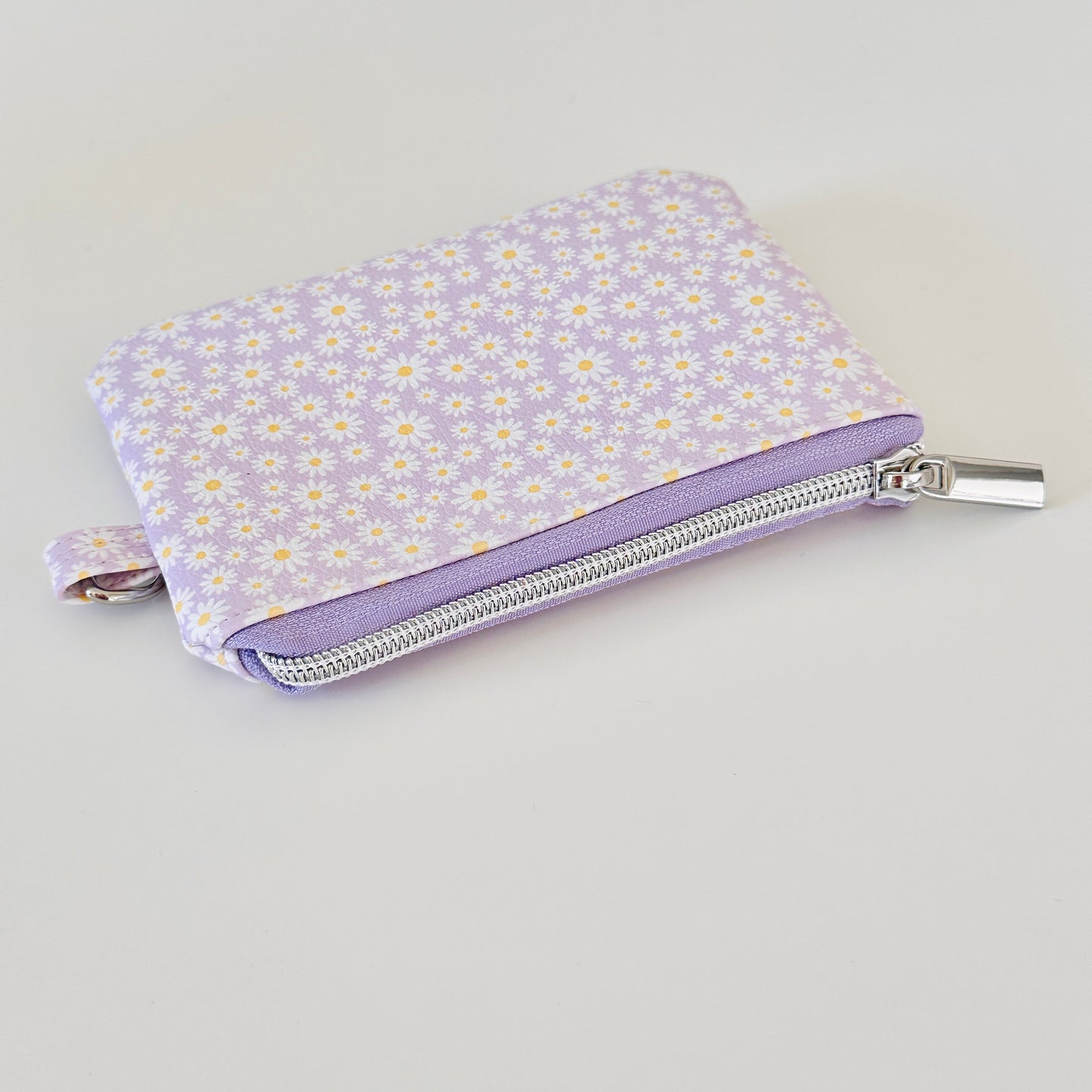 Purple floral-patterned coin purse with coins on a light gray background
