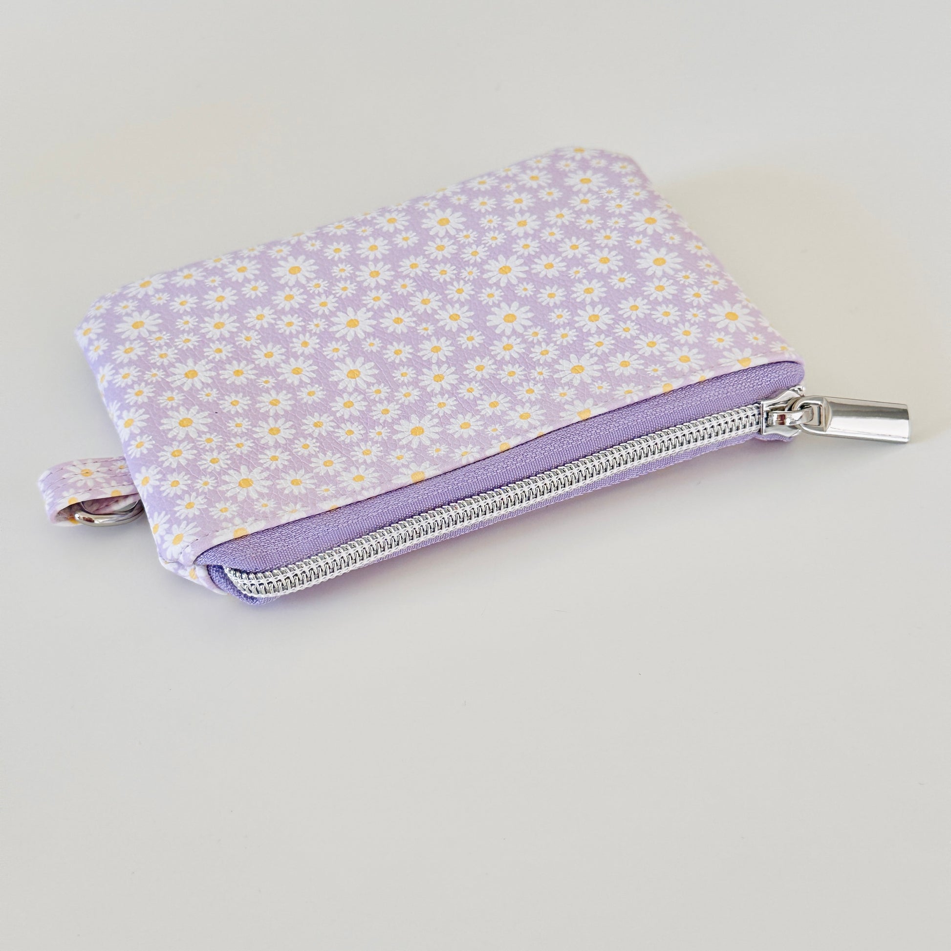 Purple floral-patterned coin purse with coins on a light gray background