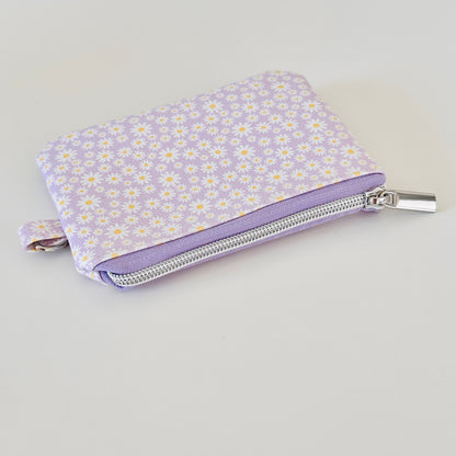 Purple floral-patterned coin purse with coins on a light gray background
