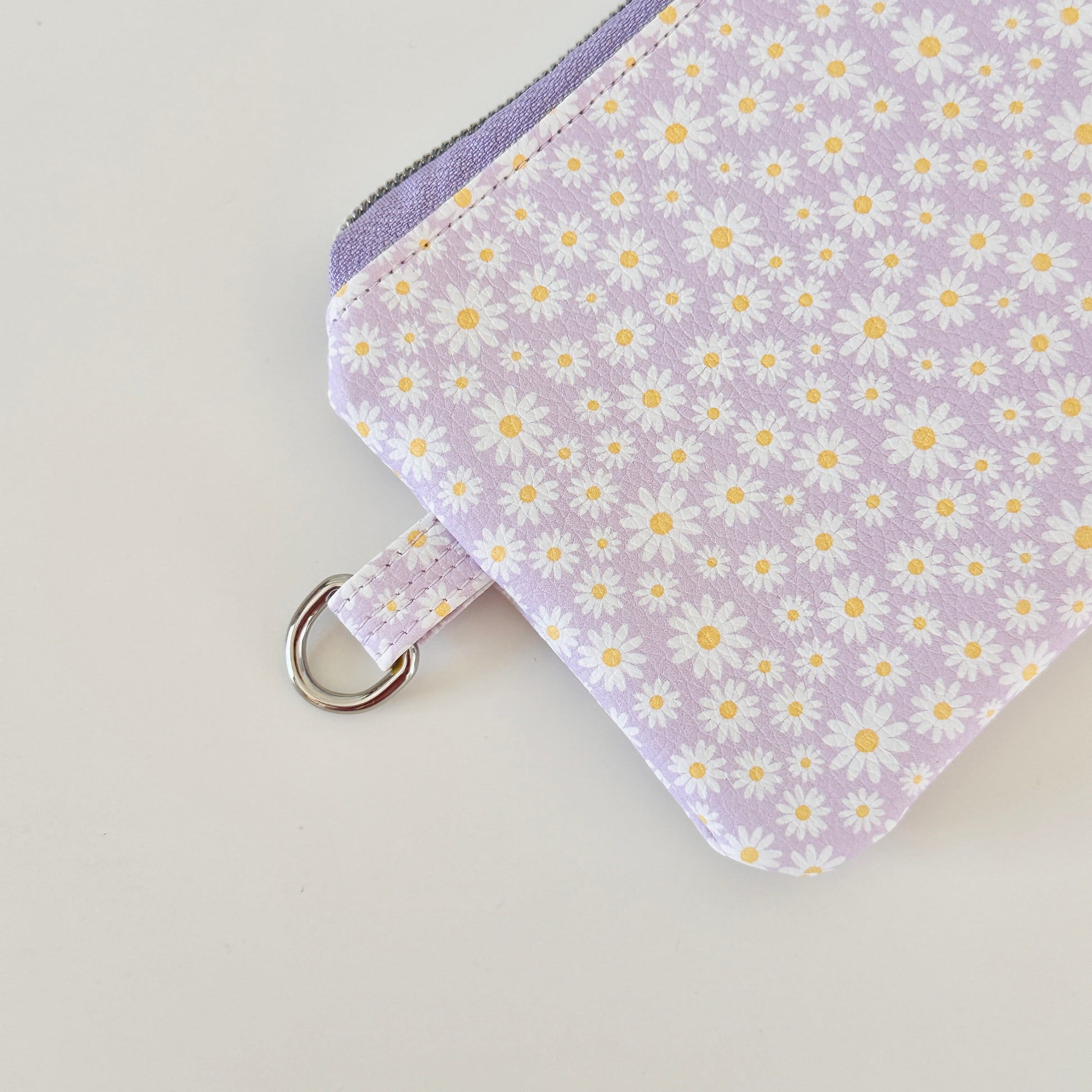Purple floral-patterned coin purse with coins on a light gray background