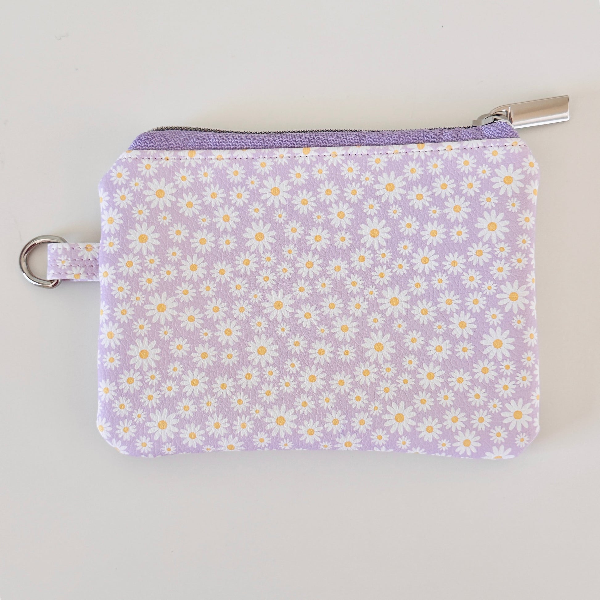 Purple floral-patterned coin purse with coins on a light gray background
