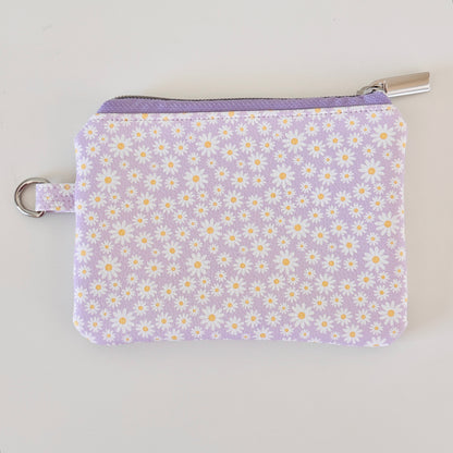 Purple floral-patterned coin purse with coins on a light gray background