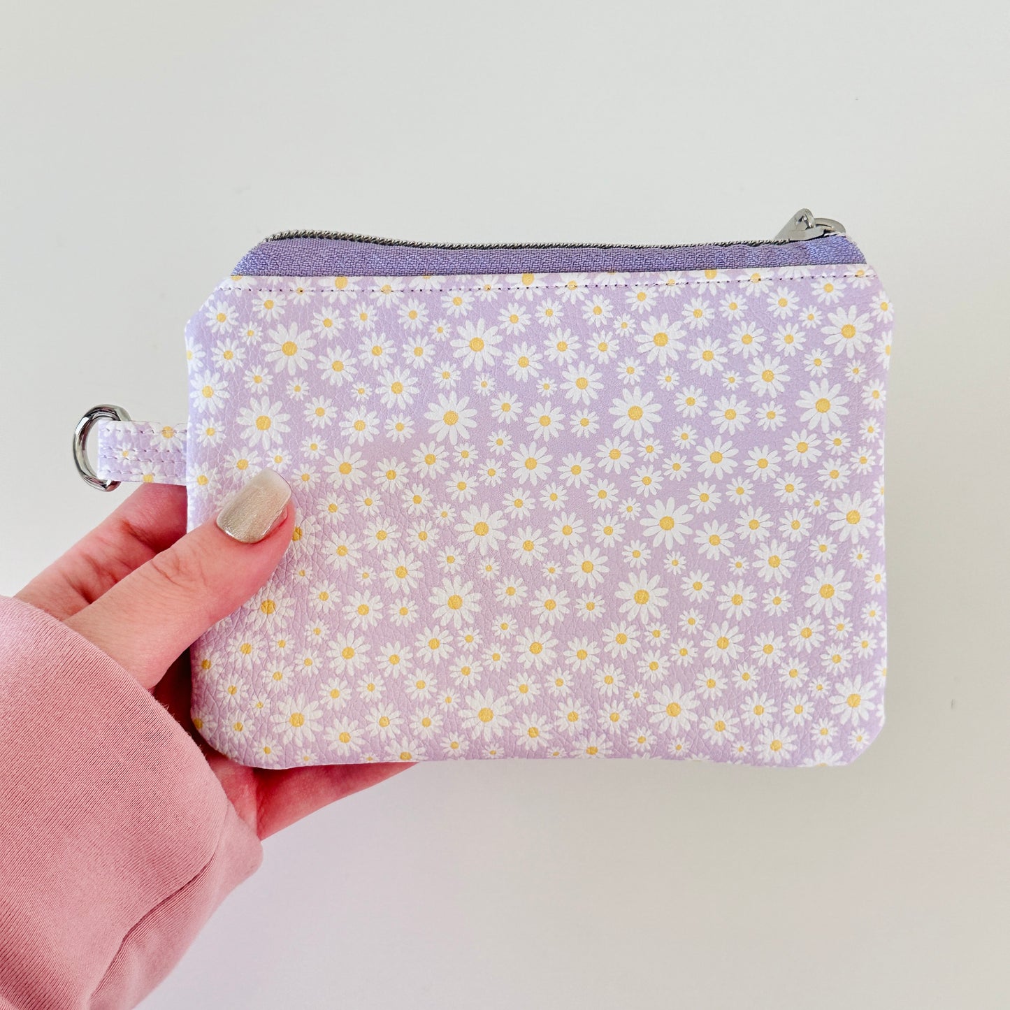 Purple floral-patterned coin purse with coins on a light gray background