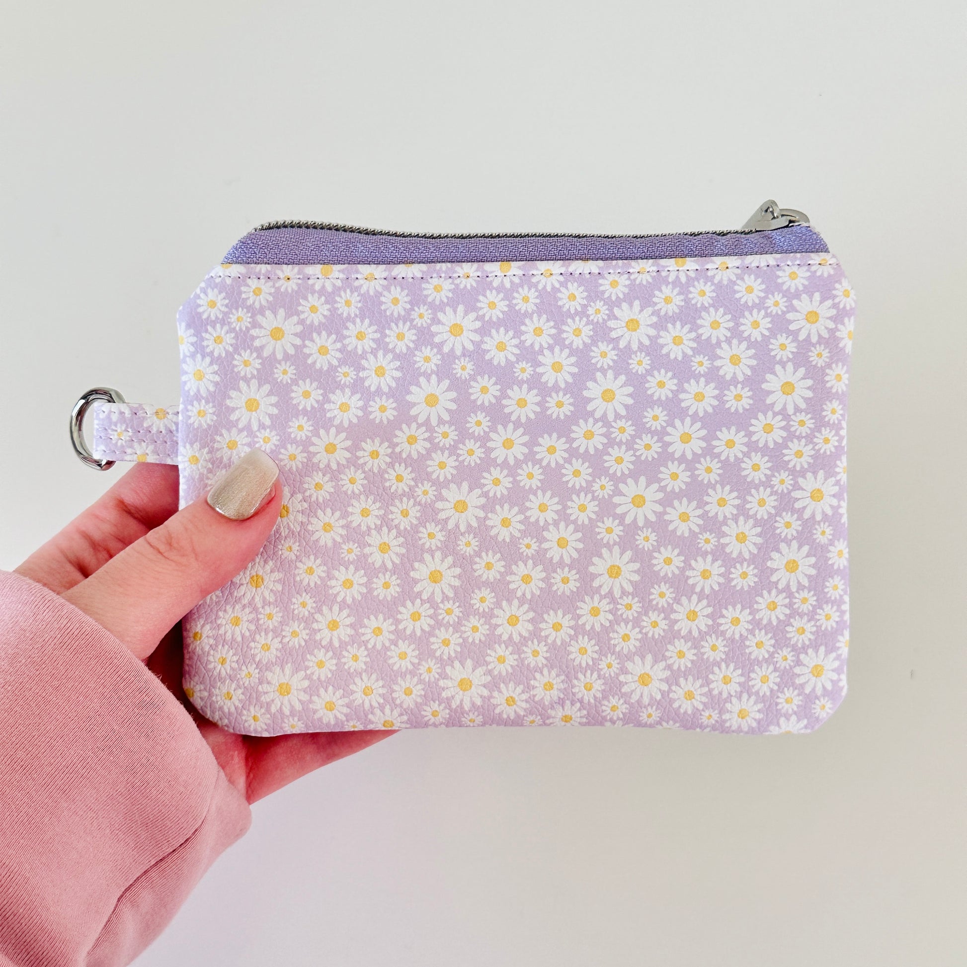 Purple floral-patterned coin purse with coins on a light gray background