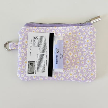 Purple floral-patterned coin purse with coins on a light gray background