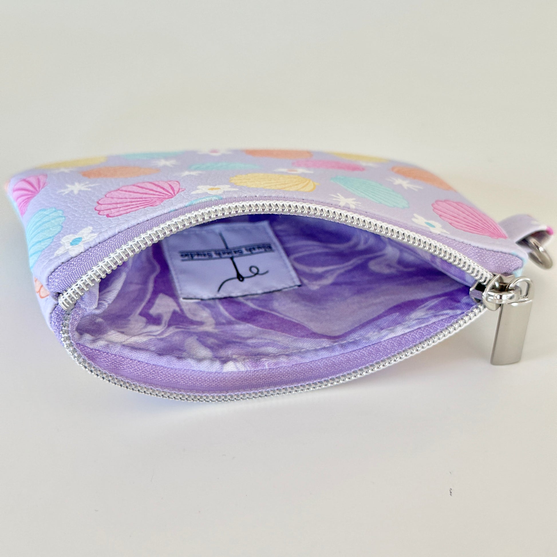 purple vegan leather coin purse with seashell pattern on a white background