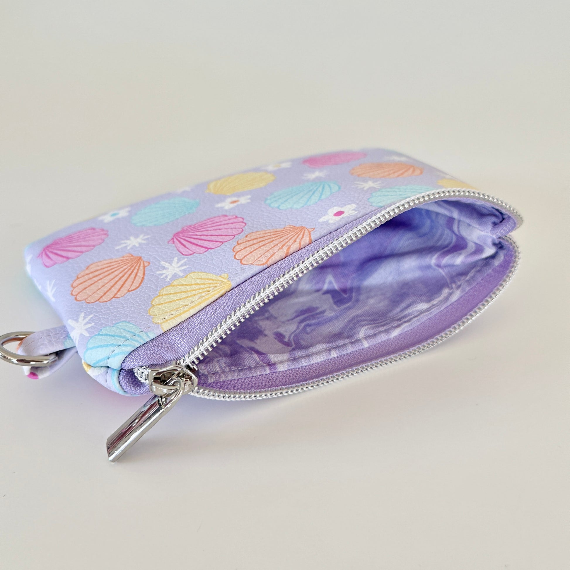 purple vegan leather coin purse with seashell pattern on a white background