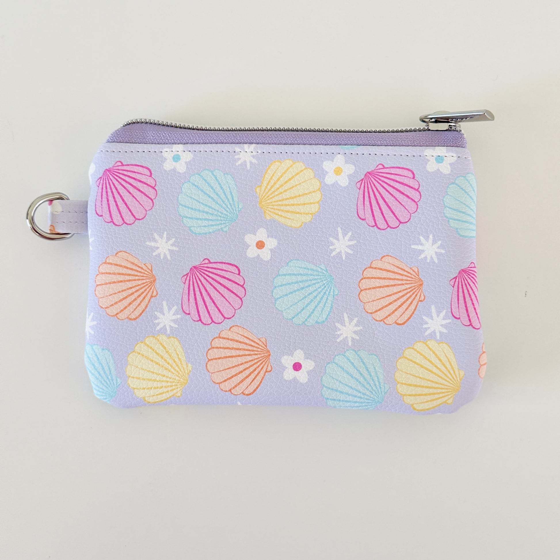 purple vegan leather coin purse with seashell pattern on a white background