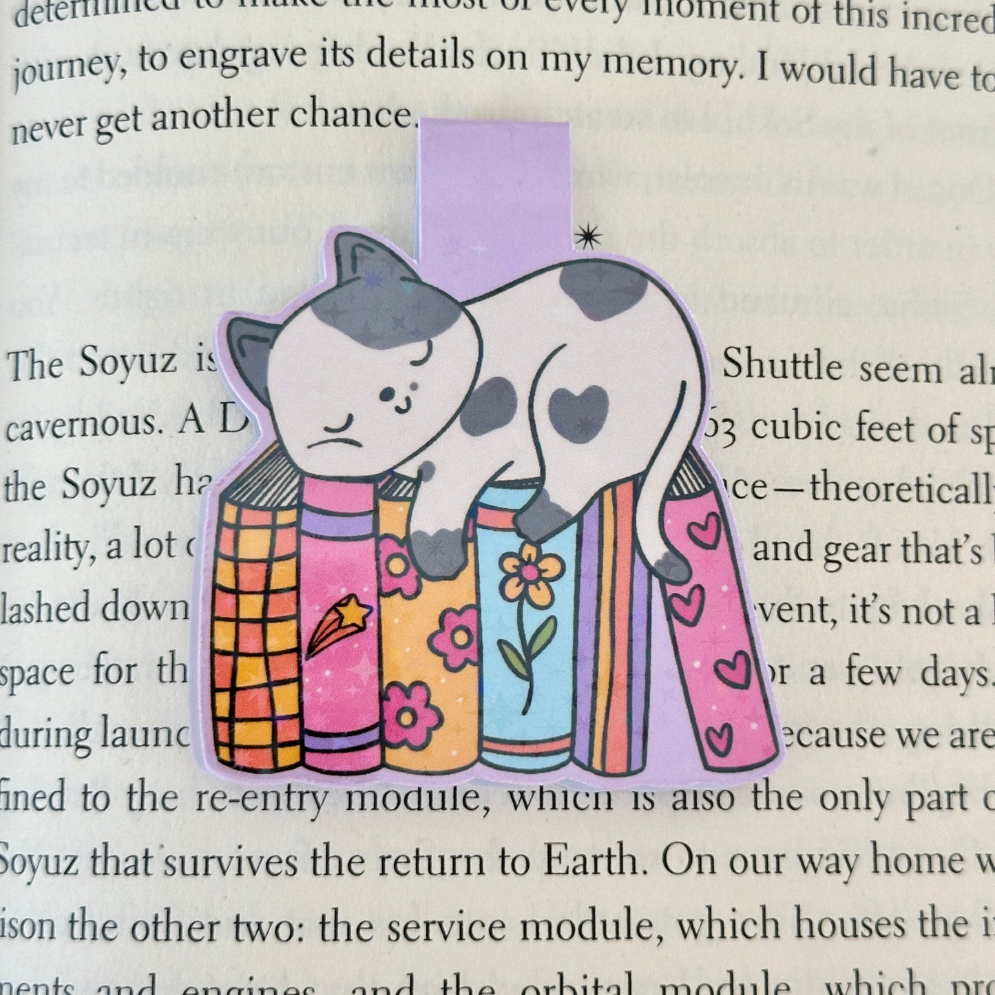 Magnetic bookmark with cat design on a Blush Stitch Studio card, held against a fluffy gray background.