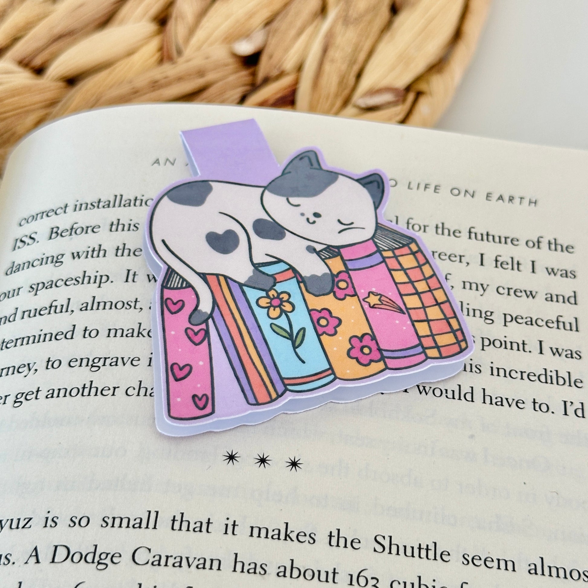 Magnetic bookmark with cat design on a Blush Stitch Studio card, held against a fluffy gray background.