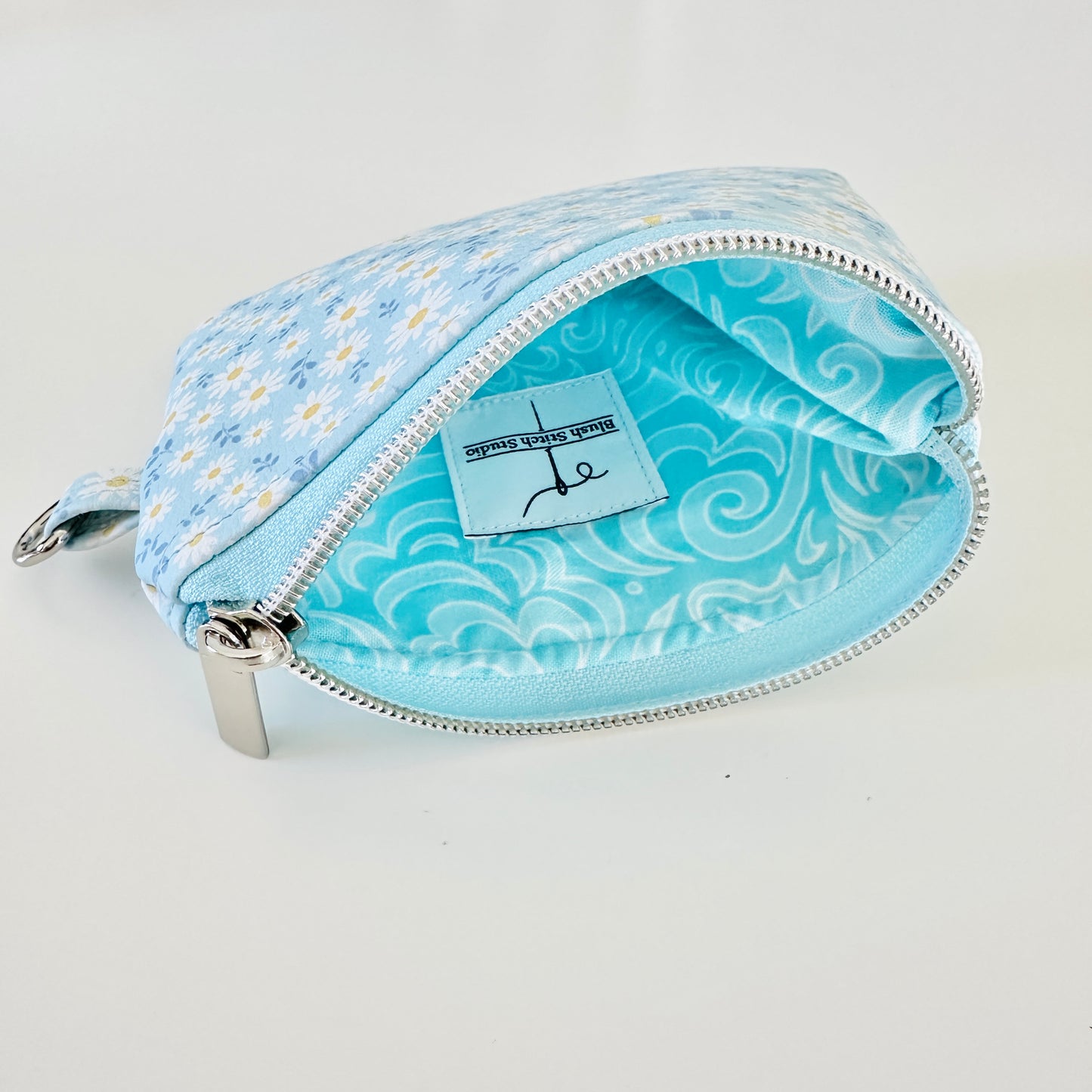 blue daisy Floral-patterned coin purse  with coins and cards on a light background