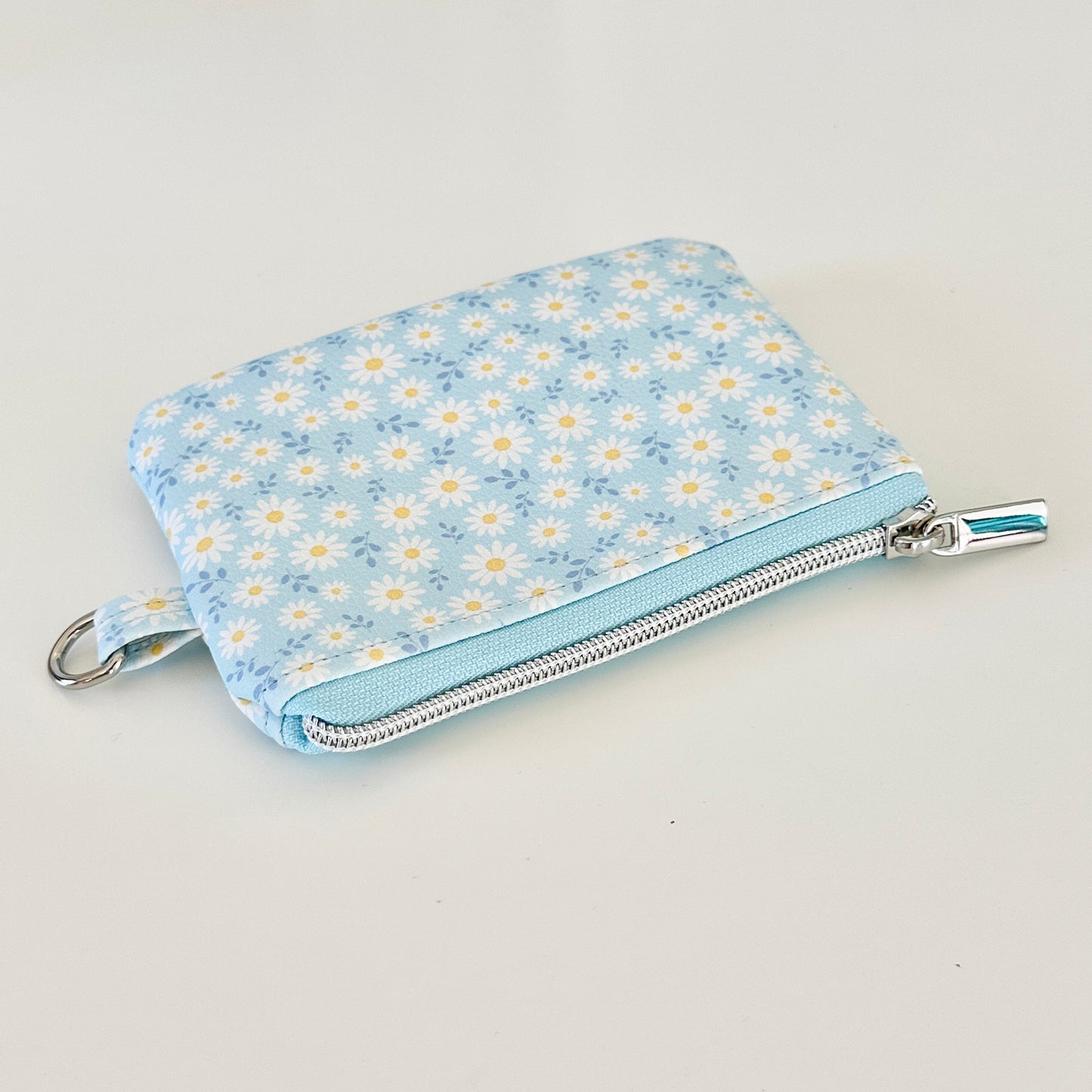 blue daisy Floral-patterned coin purse  with coins and cards on a light background